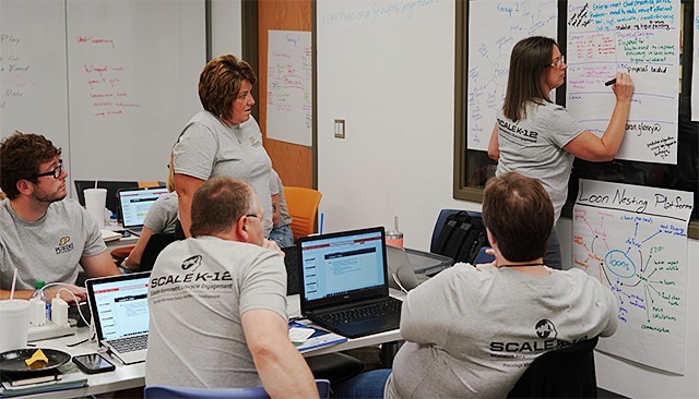 Teachers in branded shirts brainstorming on chart paper